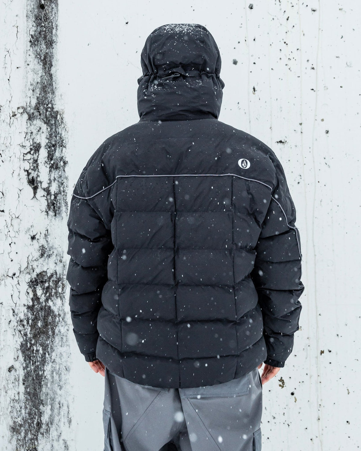 Men's quilted puffer jacket with hood, back view, shown in snowy outdoor setting