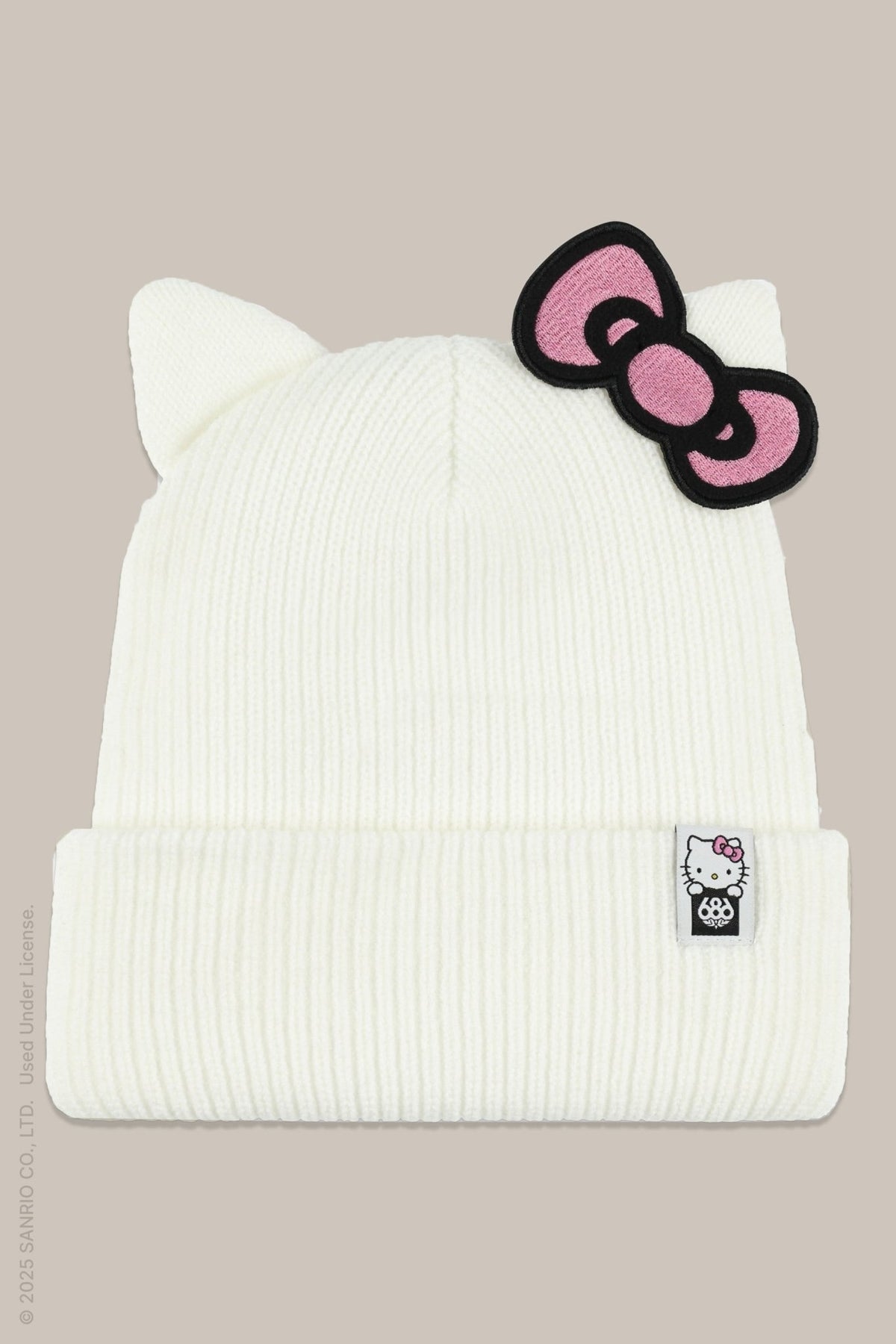 White ribbed knit beanie with cat ears, pink Hello Kitty bow patch, and branded label