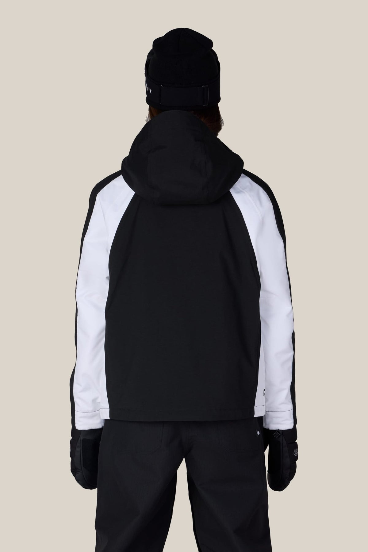 Women's shell ski jacket with hood shown from the back on a model, featuring colorblock panels
