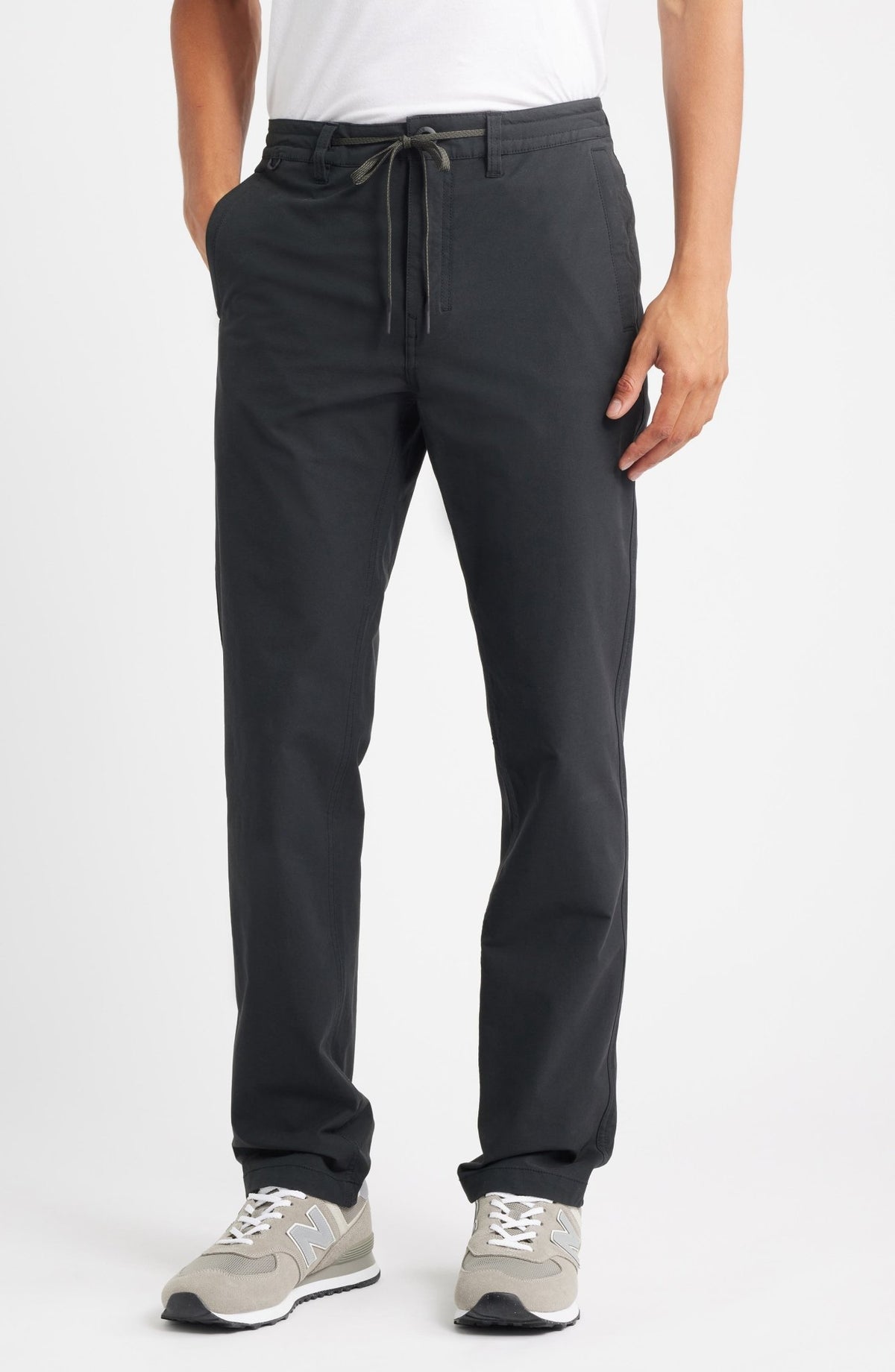 Roark men's black slim-fit travel pants with drawstring waist and New Balance sneakers