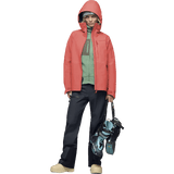 Women's hooded Gore-Tex ski jacket worn with black pants and ski boots on white background.