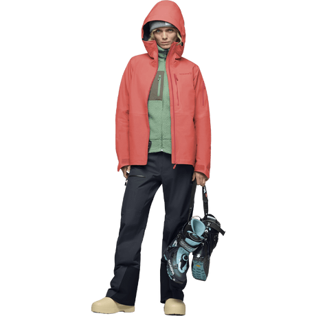 Women's hooded Gore-Tex ski jacket worn with black pants and ski boots on white background.