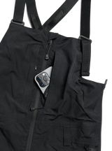Women's bib snow pants with adjustable straps, zipper pocket, and phone storage detail