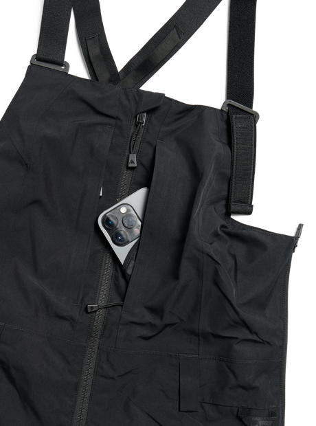 Women's bib snow pants with adjustable straps, zipper pocket, and phone storage detail