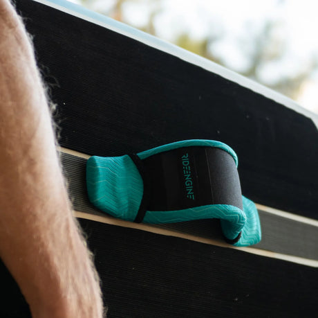 Green padded foot strap attached to a black SUP or kiteboard, close-up view