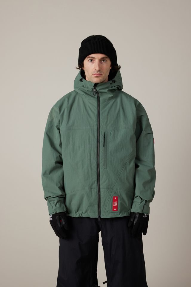 686 men's shell jacket with hood, front zip closure, and glove cuffs on model