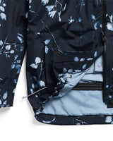 Women's Gore-Tex snowboard jacket detail showing floral print exterior, light blue lining, and zipper pocket