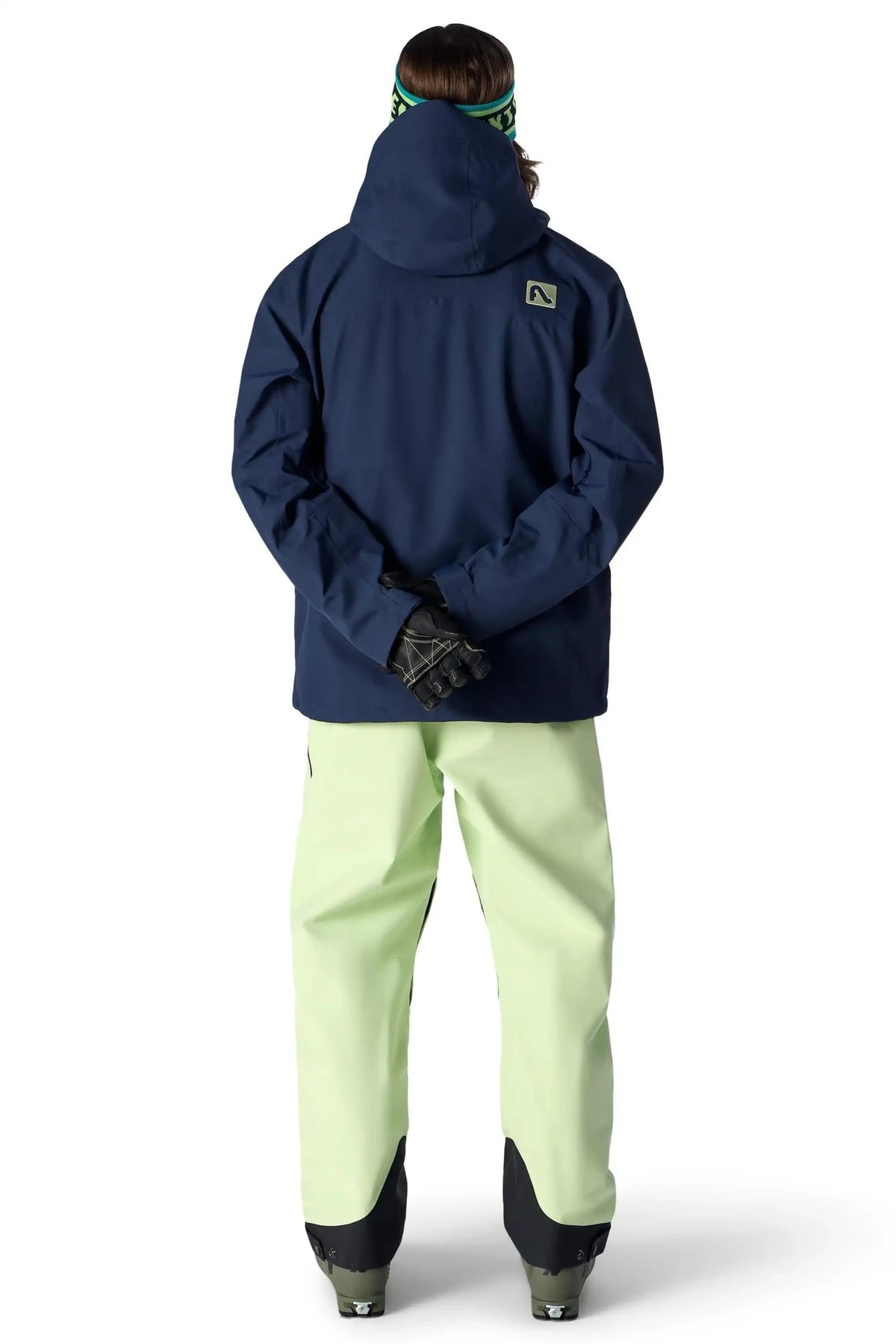 Men's ski jacket in navy blue shown from behind with matching snow pants and gloves