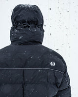 Volcom men's insulated hooded jacket with reflective piping detail, shown from back in snowy conditions.