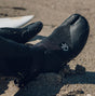 Black split toe surf boots on sand with visible logo, ideal for cold water and beach use