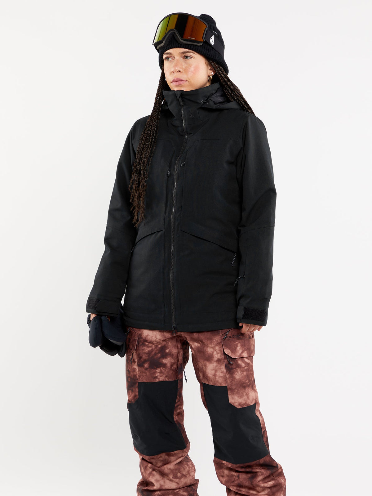 Women's technical snow jacket with hood, worn with ski goggles and patterned pants.