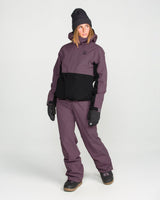 Women's insulated two-tone snowboard jacket with hood, worn with matching pants and gloves.