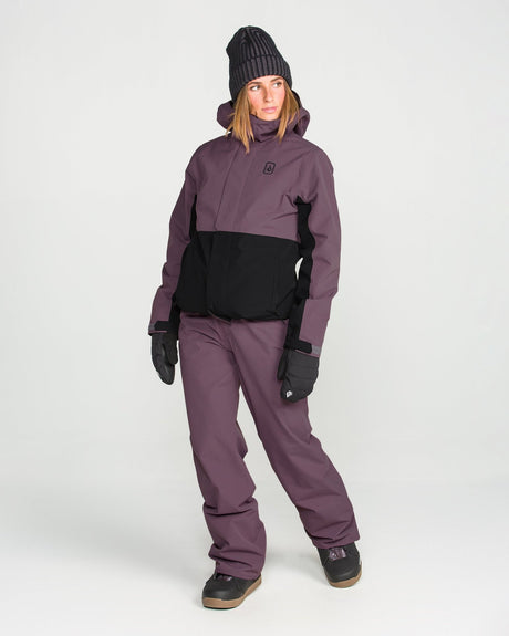 Women's insulated two-tone snowboard jacket with hood, worn with matching pants and gloves.