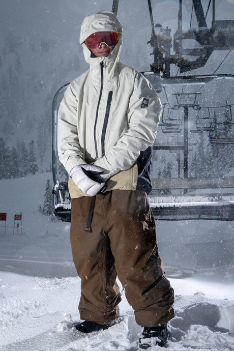 Men's insulated Gore-Tex ski jacket with hood and goggles worn at snowy mountain resort