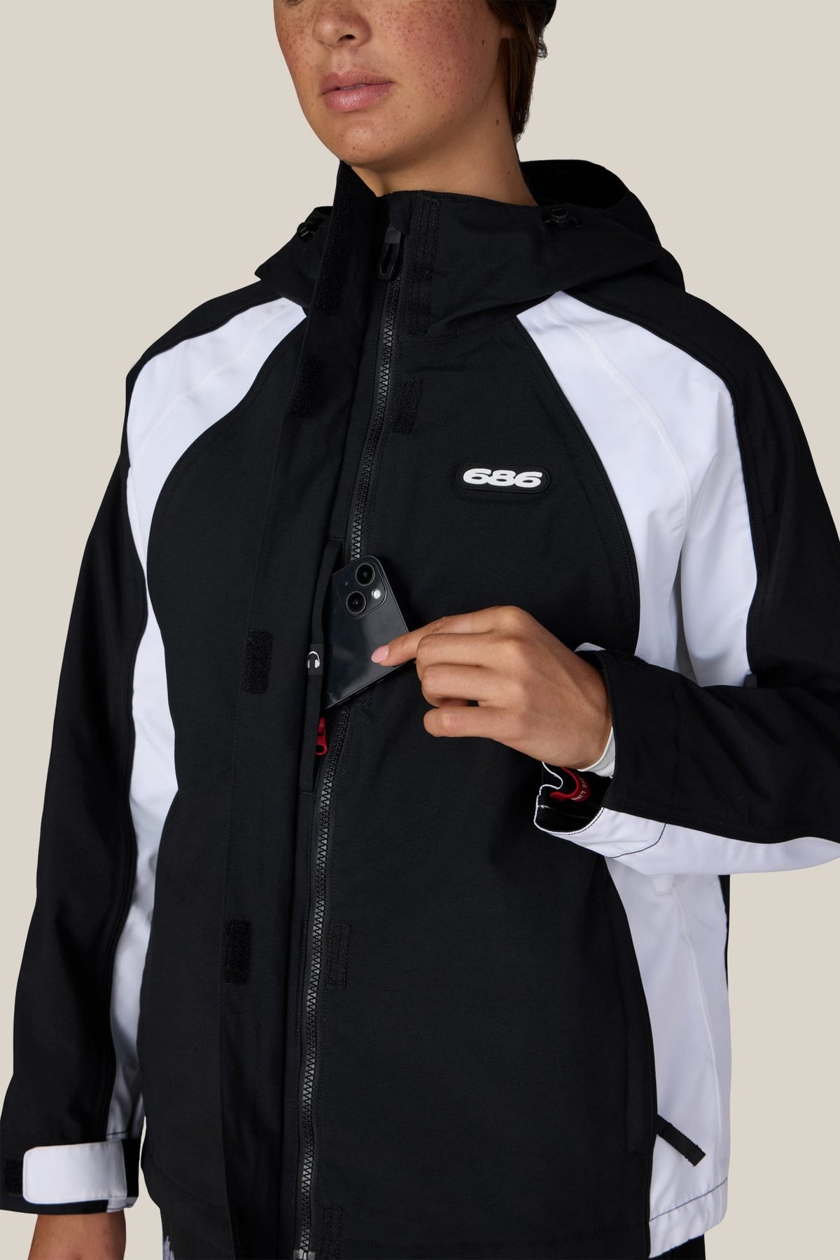 686 women's shell jacket with hood, chest pocket, and zip closure shown on model