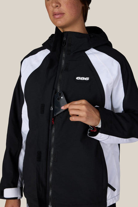 686 women's shell jacket with hood, chest pocket, and zip closure shown on model