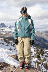 Women's shell ski jacket with colorblock panels worn on snowy mountain summit