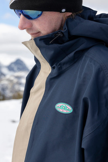 Men's ski jacket with colorblock panels, hood, and oval logo patch on chest