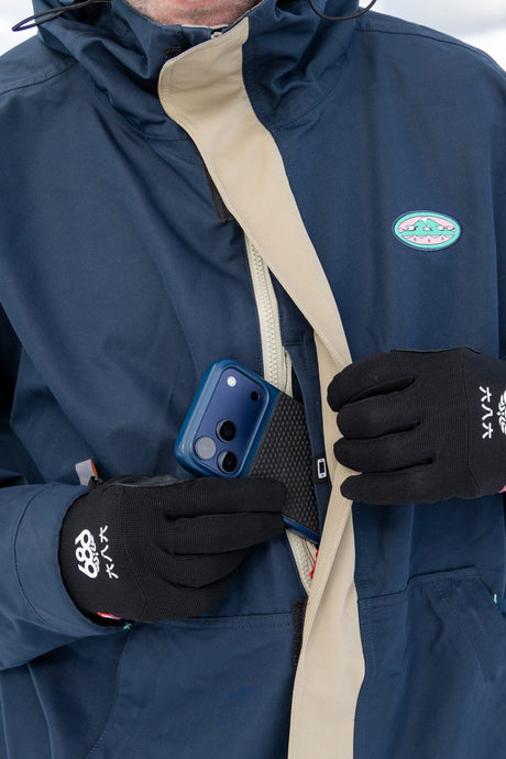 686 men's ski jacket shown open revealing interior pocket with phone storage and gloved hands