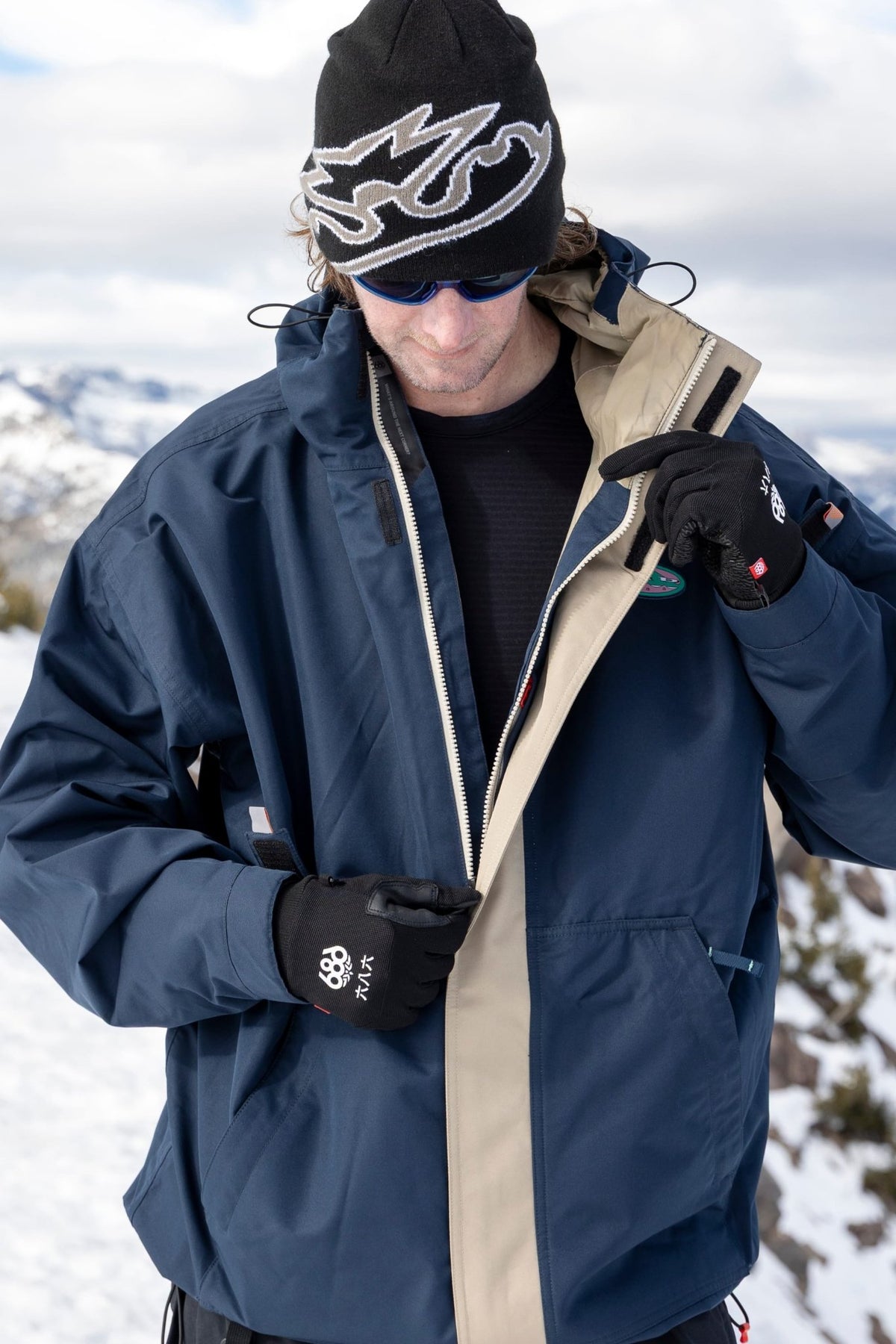 Men's ski jacket with zip opening shown in outdoor snowy mountain setting on model