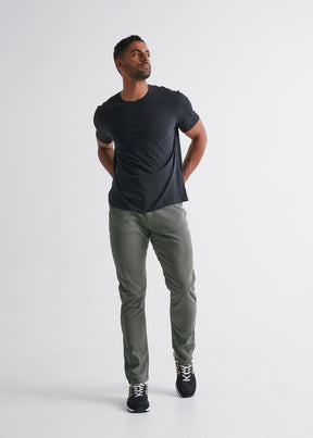 Men's olive tapered athletic pants paired with black t-shirt and navy sneakers