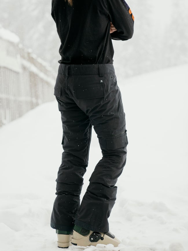 Women's insulated ski pants with cargo pockets shown from behind in snowy setting