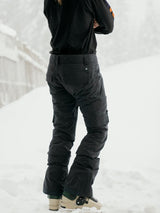 Women's insulated ski pants with cargo pockets shown from behind in snowy setting