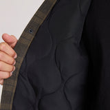 Close-up interior view of women's plaid jacket showing quilted black lining and snap closure