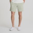 Men's sage green cotton shorts with patch pockets and white sneakers